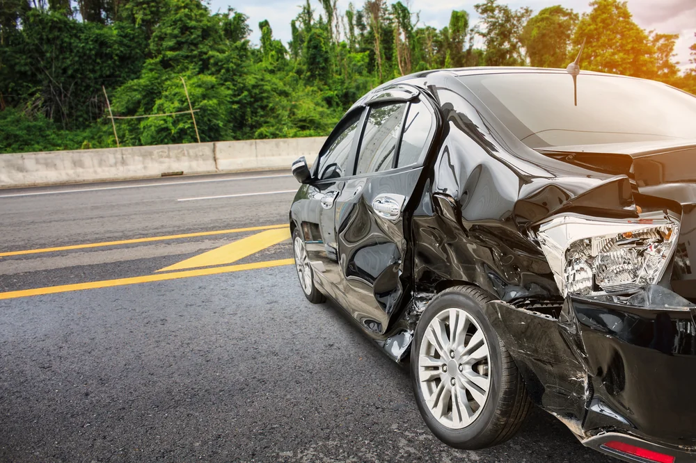 Black sedan with rear-end collision damage on roadside ready for insurance claim repair — TKM Smash Repairs, Edmonton QLD
